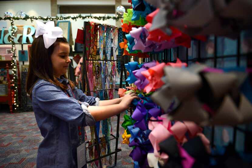 Reece Tucker, 6, adjusts hair bows in a booth at the 'Neath the Wreath Holiday Gift Market...