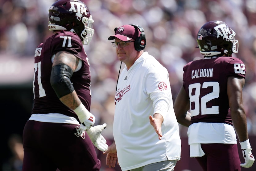 Texas A&M head coach Mike Elko, center, celebrates with players as they walk off the field...