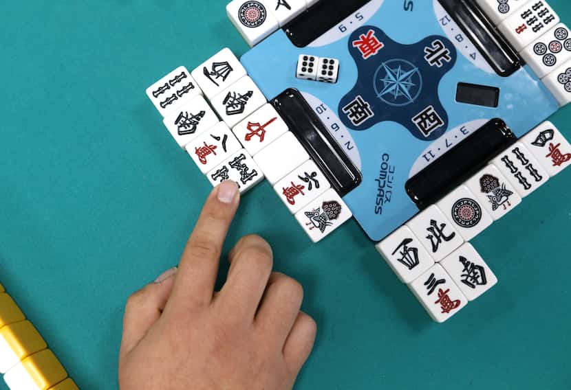 Brandon Castaneda slides a tile into place while playing a game of riichi mahjong. 