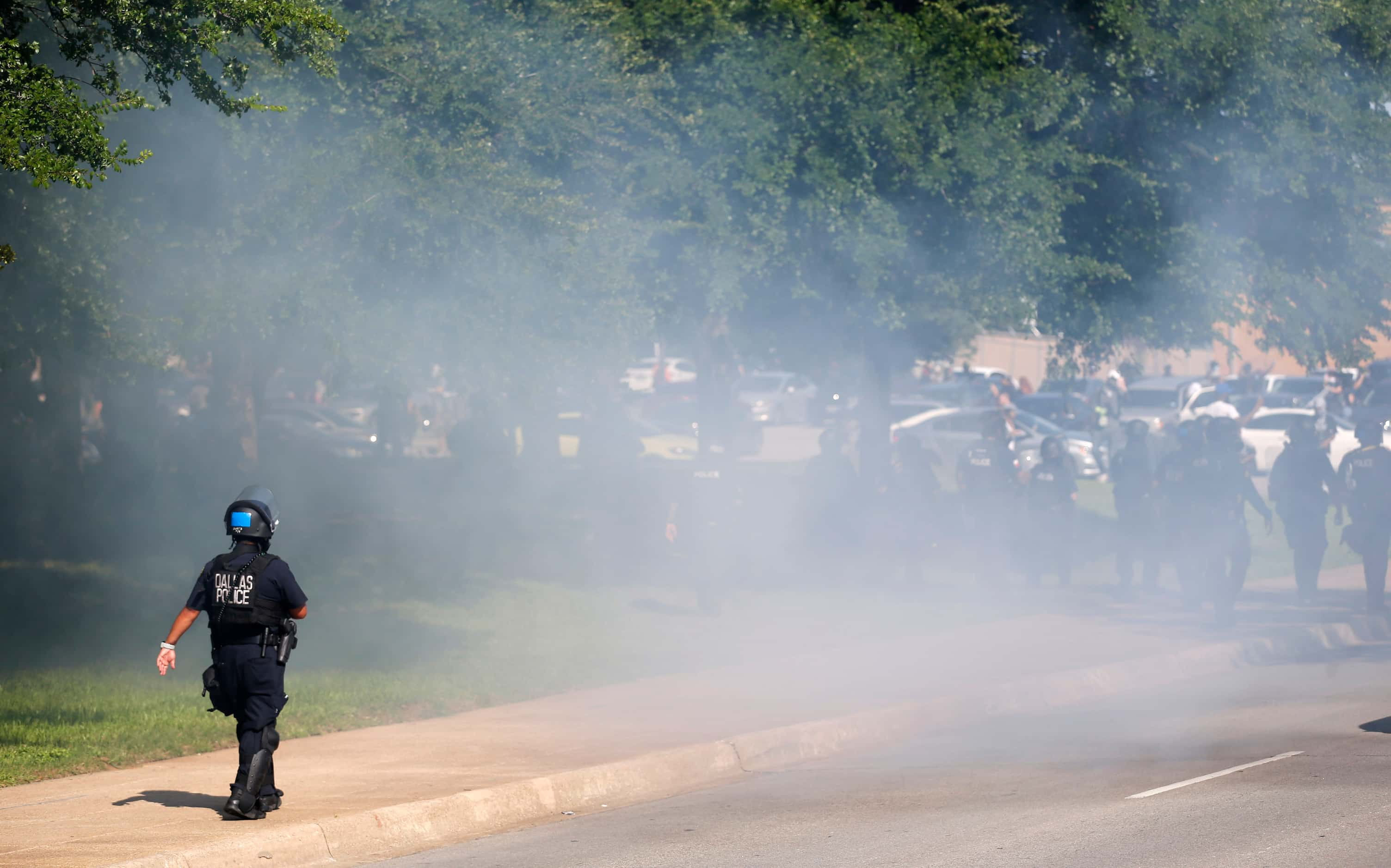 A Dallas police officer walks up the Akard Street as police move the crowd away from Dallas...