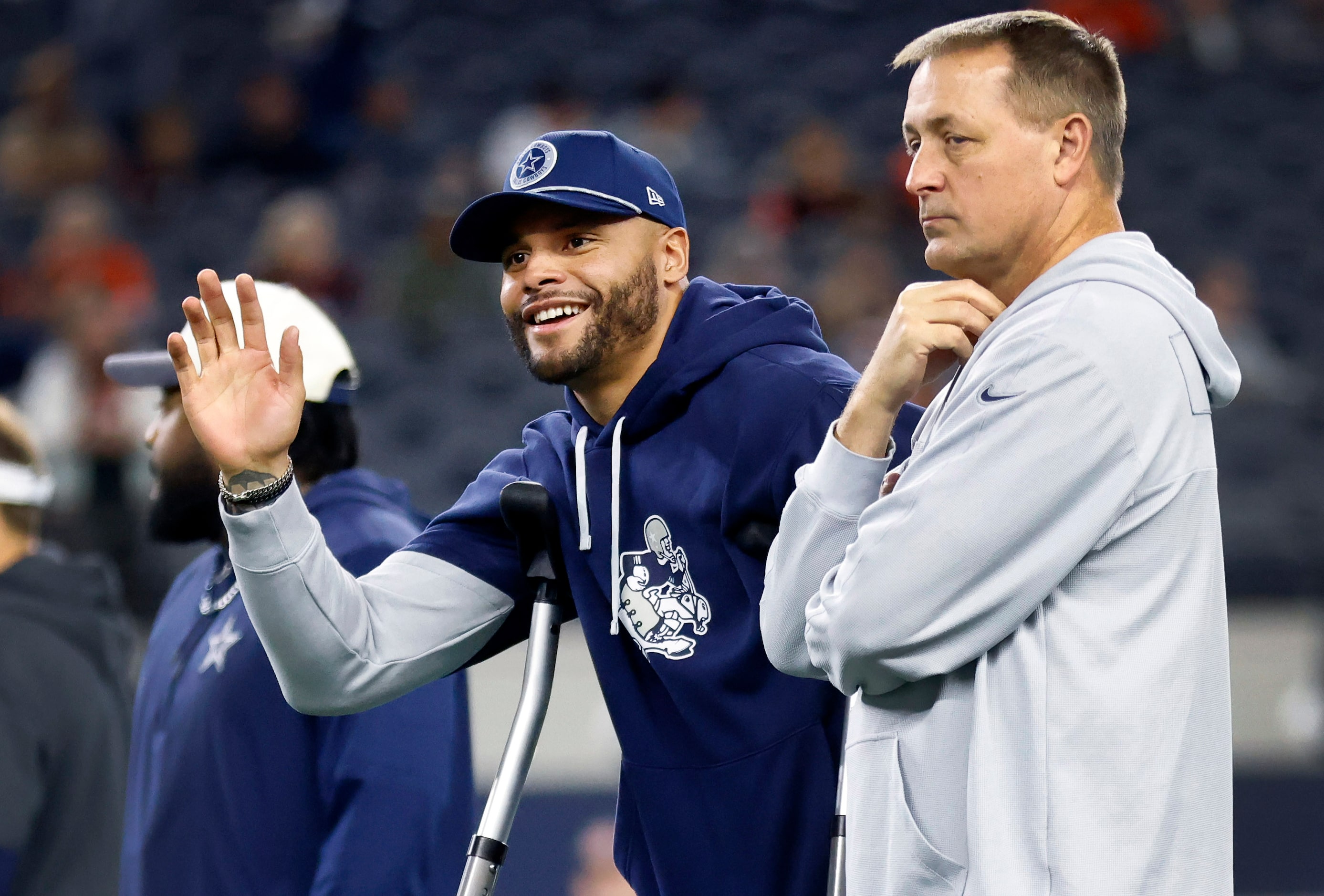 Injured Dallas Cowboys quarterback Dak Prescott (left) waves to the sideline during pregame...