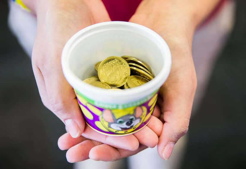 
Employee Adriana Morales holds a container of tokens at Chuck E Cheese on Wednesday, April...
