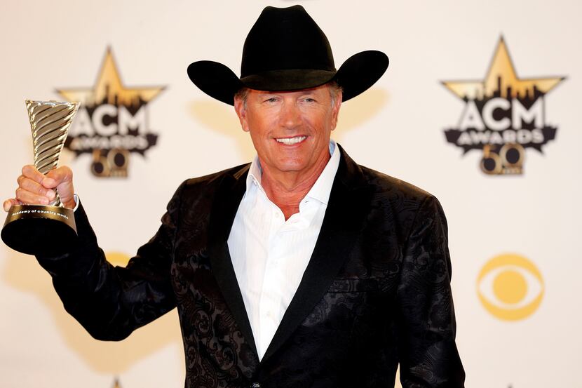 George Strait poses for a photo with his Milestone Award during the 2015 Academy of Country...