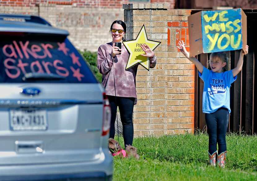 Piper Riggs (right), 8, and her mother Jessica wave as teachers from Walker Elementary...