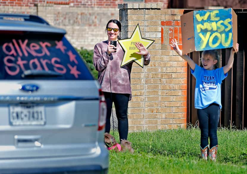 Piper Riggs (right), 8, and her mother Jessica wave as teachers from Walker Elementary...