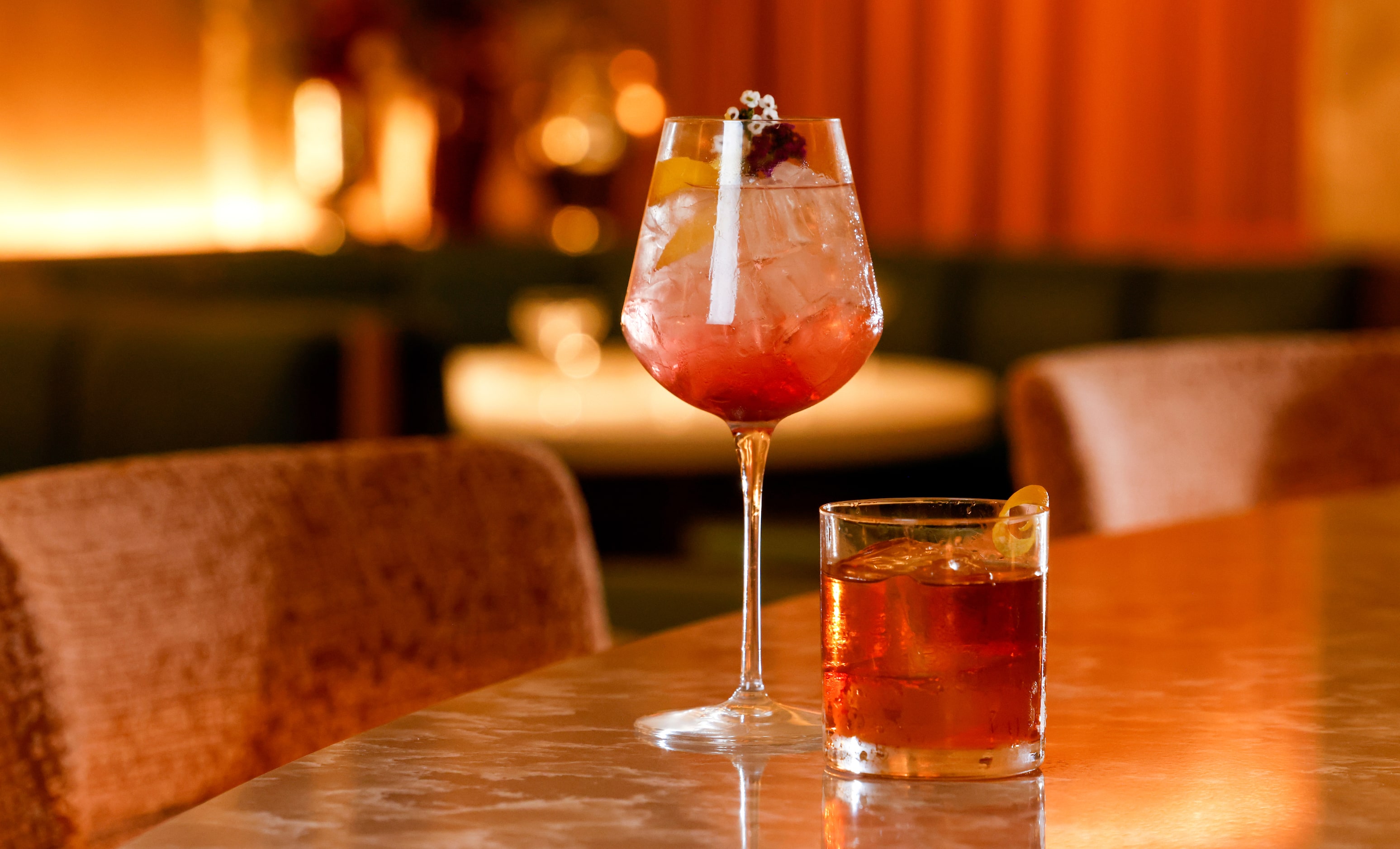 Champagne cocktail Femme Fatale (left) and cognac cocktail Le Pistolet sit on the bar top of...