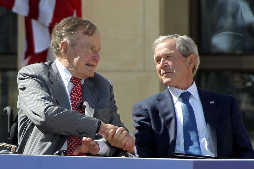 Former President George W. Bush shakes hands with his father, former President George H.W....