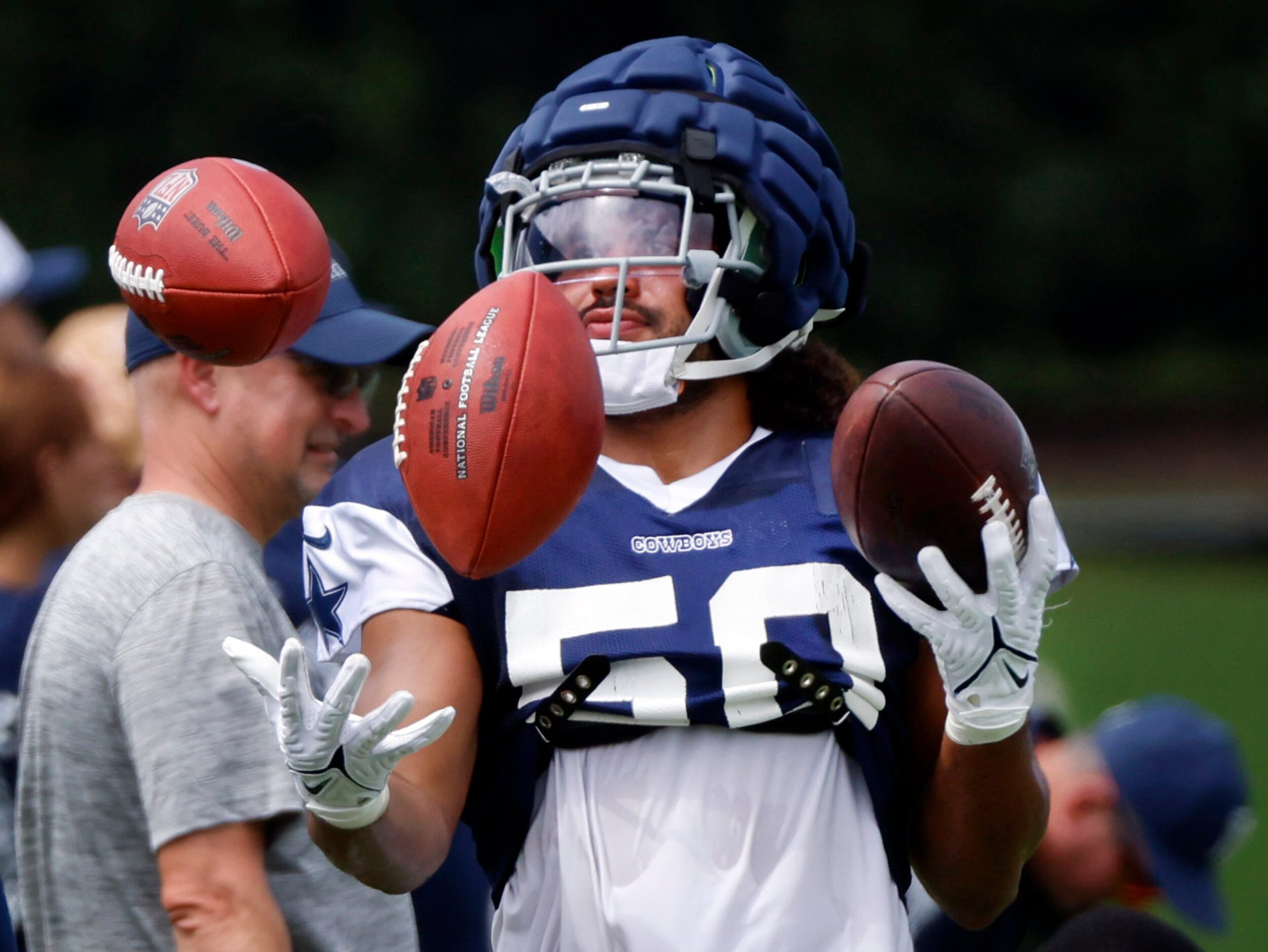 Dallas Cowboys linebacker Eric Kendricks (50) juggles three footballs on the sideline as the...