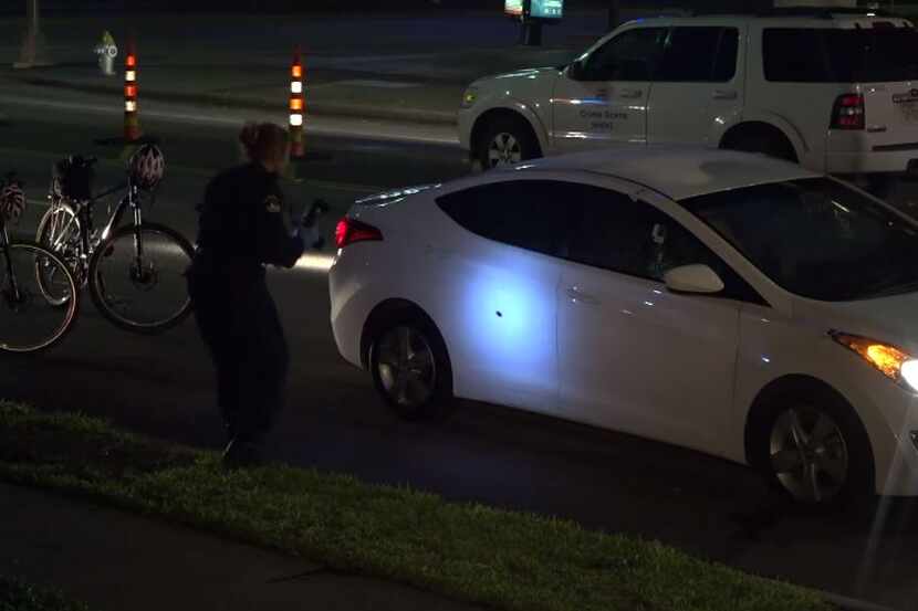 A Dallas police officer examines a bullet hole in a car caught in a shooting on Ross Avenue.
