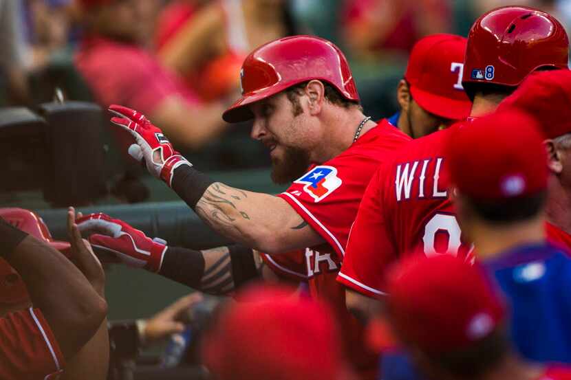 Texas Rangers left fielder Josh Hamilton (32) gets high-fives from team mates in the dugout...