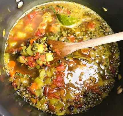Green lentil and baby kale soup simmers on the stove. (Leslie Brenner/Staff) 