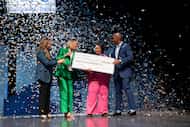 Three people hand a woman a large prize check for $60,000 while confetti falls around them.