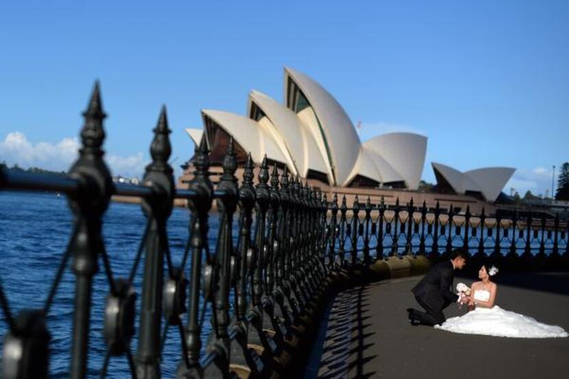 
A bride and groom pose in front of the Sydney Opera House, a relatively modern wonder built...