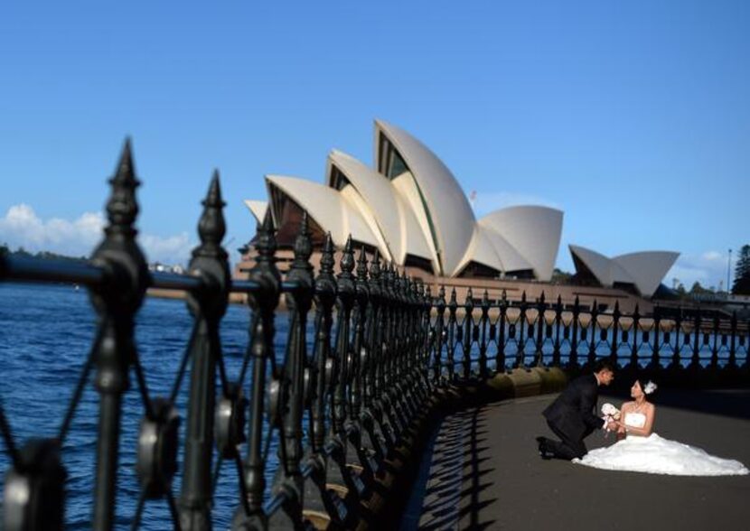 
A bride and groom pose in front of the Sydney Opera House, a relatively modern wonder built...