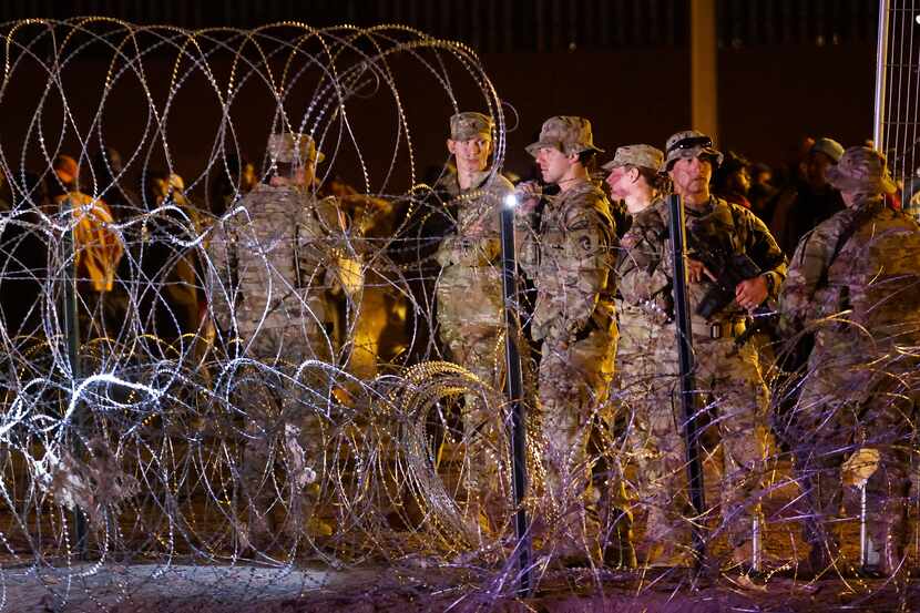 Guardsman patrol the concertina wire as migrant people waited on the U.S. side of the Rio...
