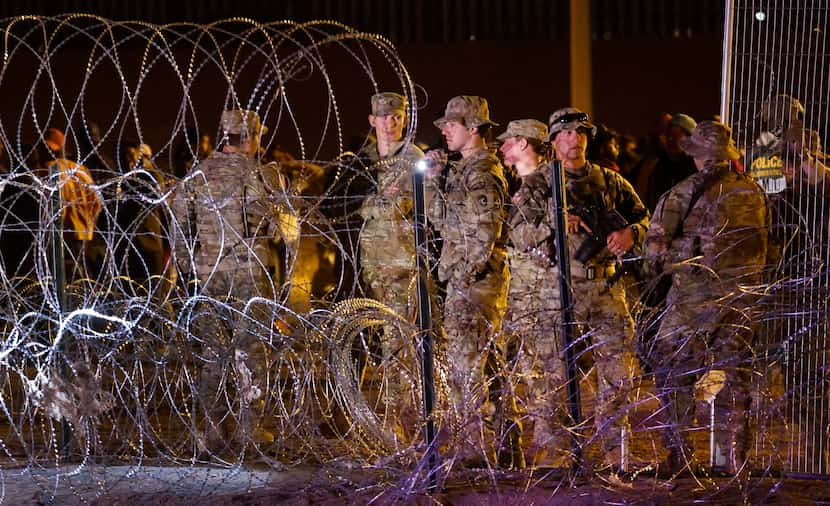 Guardsman patrol the concertina wire as migrants waited on the U.S. side of the Rio Grande...
