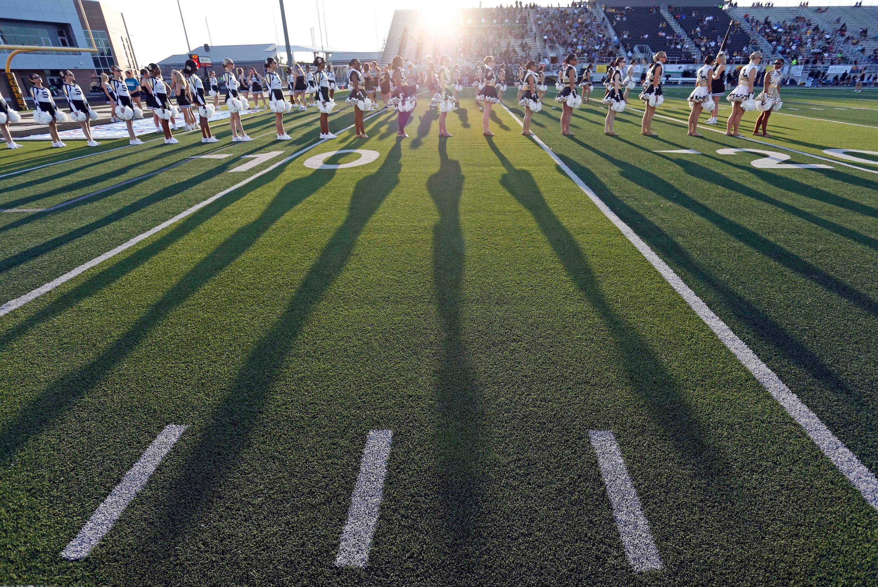 Shadows of the Forney high drill team members stand at attention in the late evening sun...