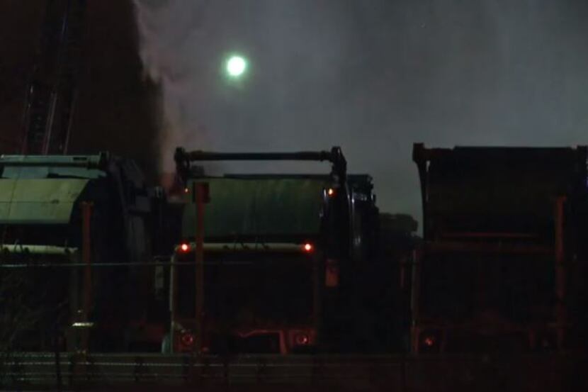Garbage trucks are doused with water after fire and explosions broke out Tuesday at a waste...