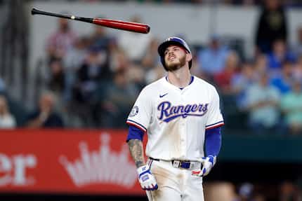 Texas Rangers designated hitter Jonah Heim tossed his bat as he winced in pain after being...
