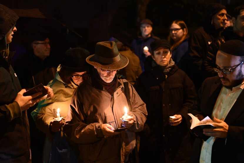 People hold candles outside the Tree of Life Synagogue after a shooting there left 11 people...