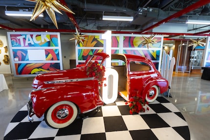 A red, vintage '30s-era car replica is on display inside a large garage space, adorned with...