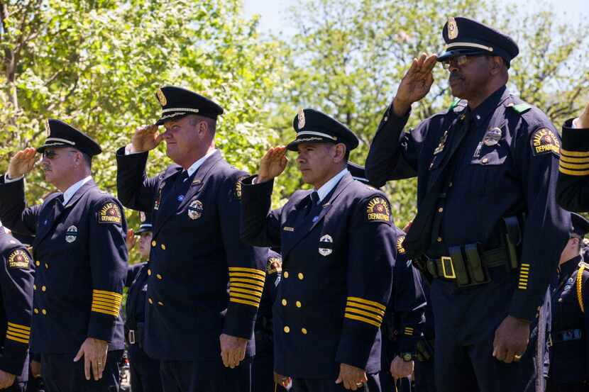 Dallas, Texas law enforcement officers salute as names of Texans are read during a roll call...