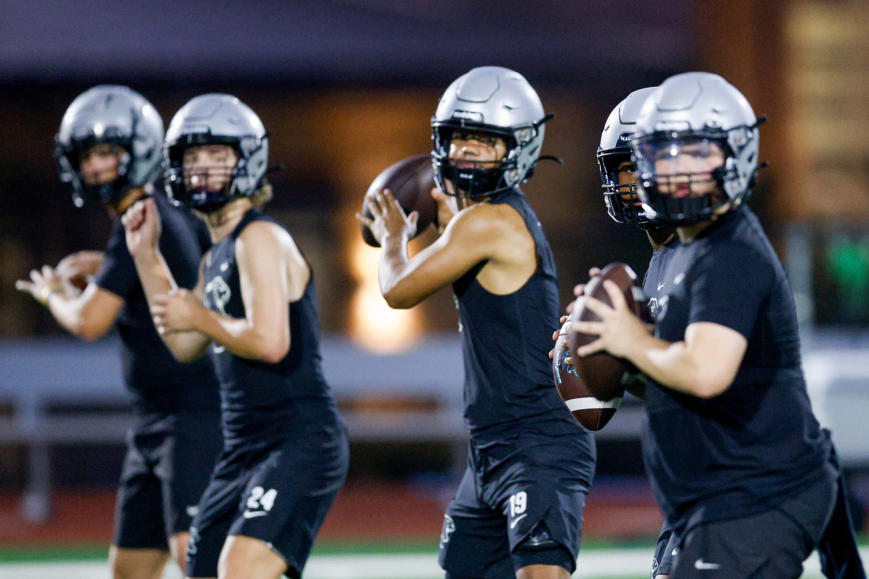 Quarterbacks run a drill during football practice at Panther Creek High School, Monday, Aug....