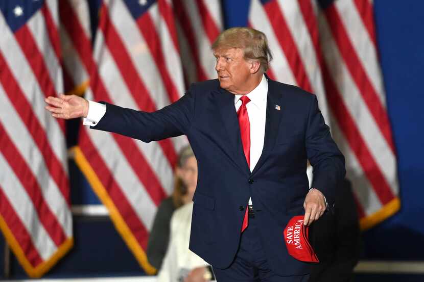 El expresidente Donald Trump arroja gorras a la multitud mientras sube al escenario durante...