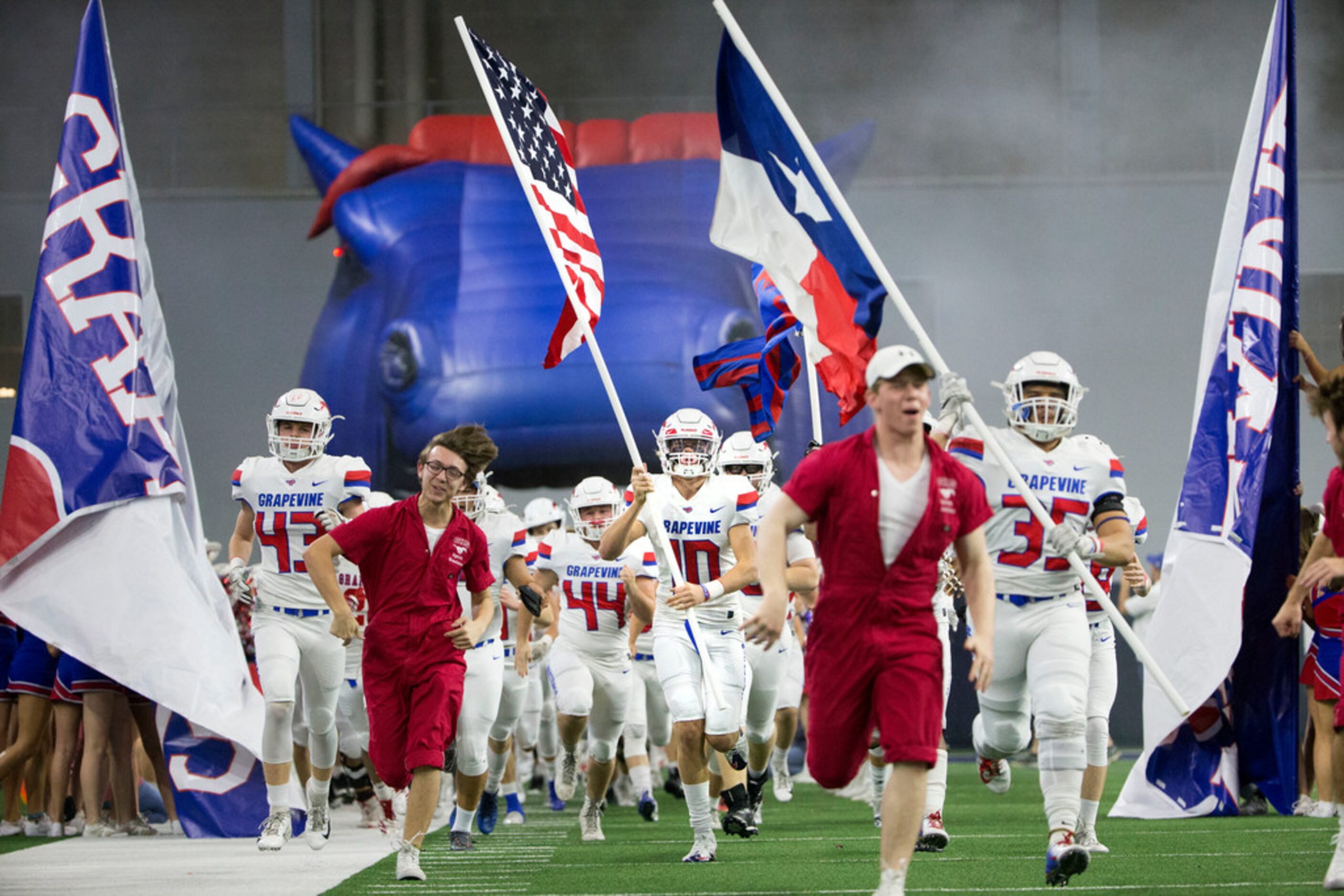 Grapevine linebacker Garrett Johnson (10) carries the U.S. flag as the team charges the...