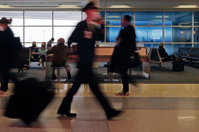 An airline pilot and passengers walk through DFW International Airport in Grapevine, Texas...