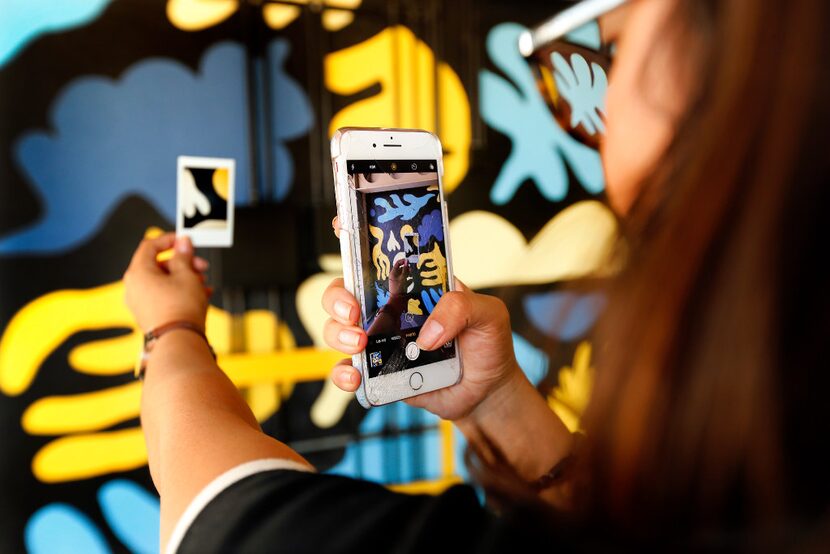 Daniela Chavez takes a photo of her Polaroid clue in front of a Kyle Steed mural she was...