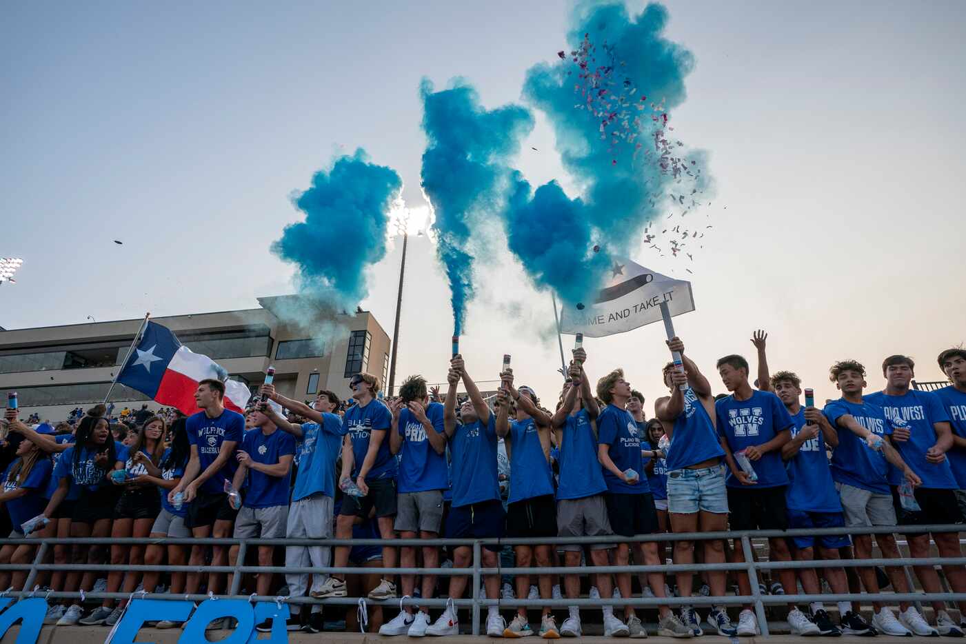 Plano West fans shoot blue powder into the air before a high school football game against...