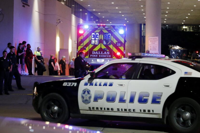 A Dallas police vehicle follows behind an ambulance carrying a patient to the emergency...