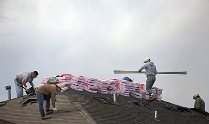 Roofers work on a home in Glenn Heights. (2016 File Photo/The Dallas Morning News)