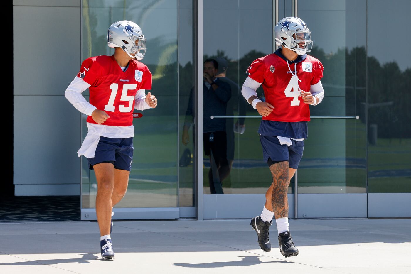 Dallas Cowboys quarterbacks Trey Lance (15) and Dak Prescott (4) jog to the field for a...