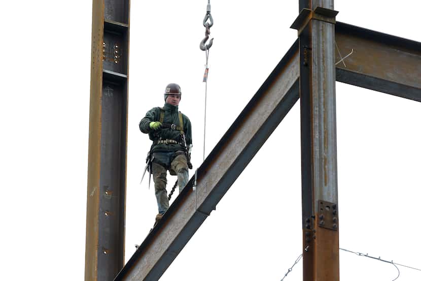 In this Tuesday, April 29. 2014 photo, a worker positions iron girders at a building...