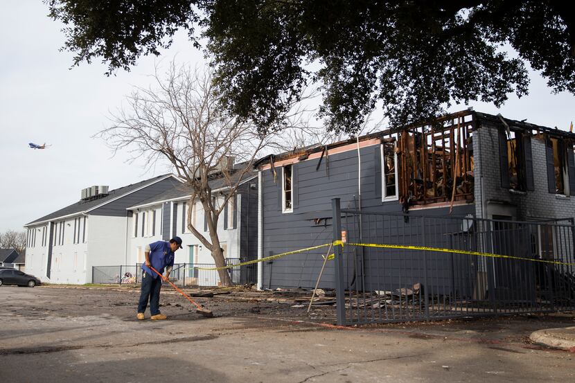 A worker begins to clean up the damage at Chase Place Apartments after a fire displaced...