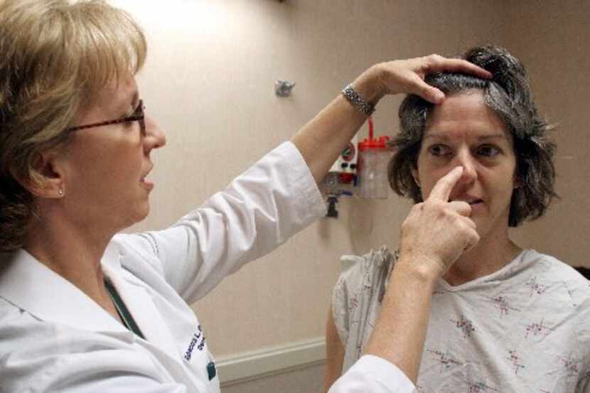 Dermatologist Rebecca Euwer examines Tracy Olsen at a skin cancer screening at Medical City...