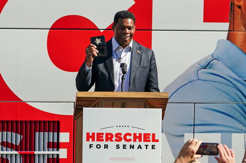 Herschel Walker, Republican candidate for U.S. Senate in Georgia, flashes a police badge as...