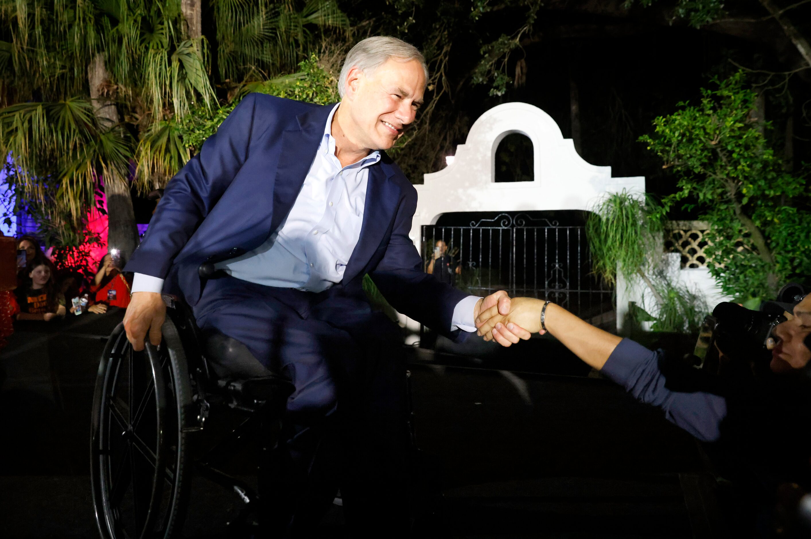 Texas Governor Greg Abbott shales hands with supporters as he arrives on stage for a victory...