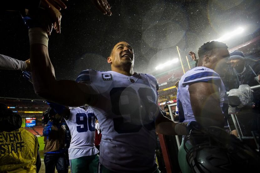Dallas Cowboys defensive end Tyrone Crawford (98) high-fives fans as he walks off the field...