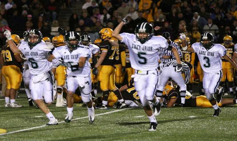 Jeff Heath celebrates with his Lake Orion High School teammates during a 34-28 victory...