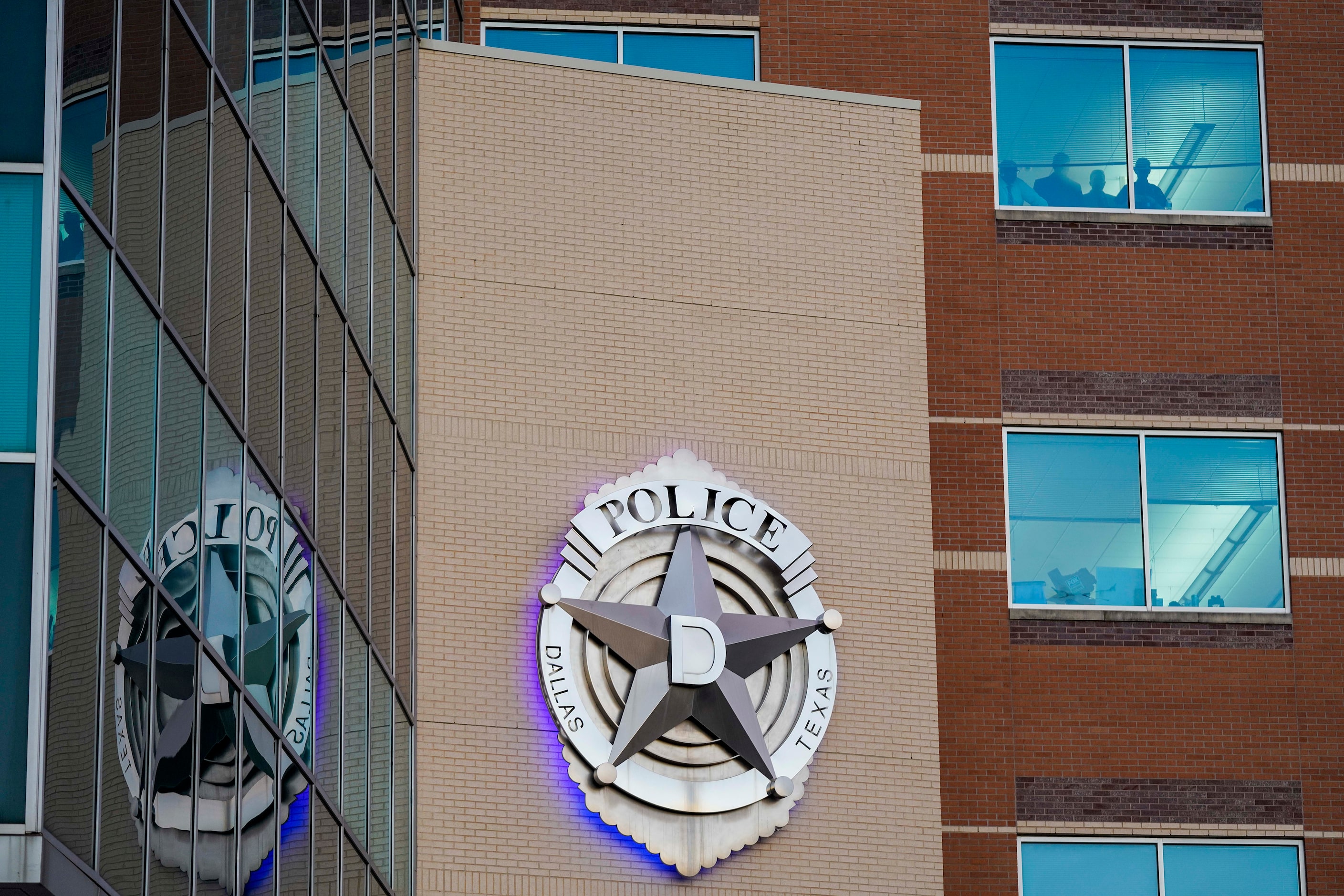 People watch from the windows of Dallas Police Headquarters during a protest against police...