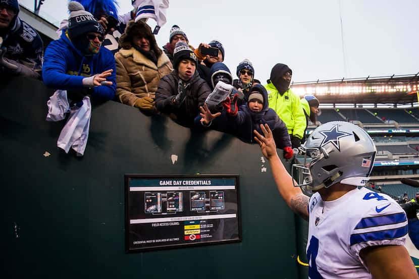 Dallas Cowboys quarterback Dak Prescott toss his wrist bands to fans as he leaves the field...