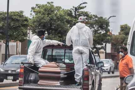 Empleados de un cementerio llevan los restos de una persona para enterrarla en Guayaquil,...