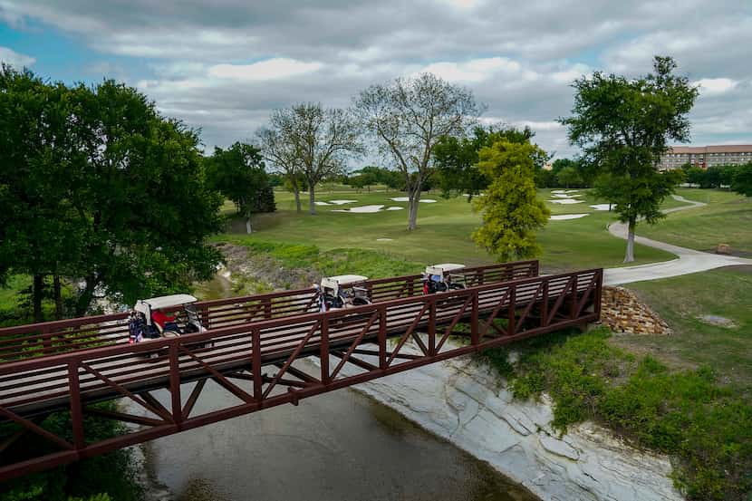 FILE - Players drive their carts across a bridge on the sixth hole at TPC Craig Ranch on...