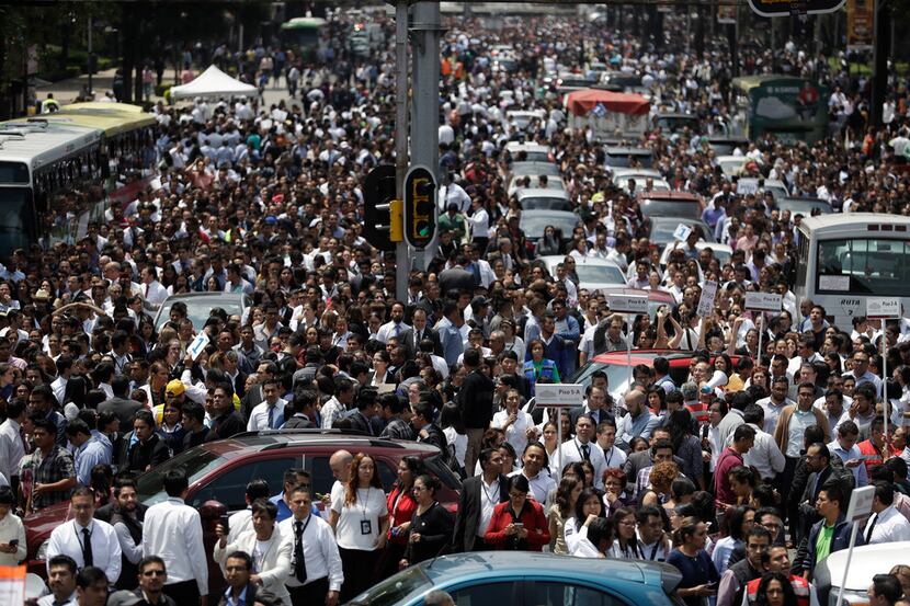 People evacuated from office buildings gather in Reforma Avenue after an earthquake in...