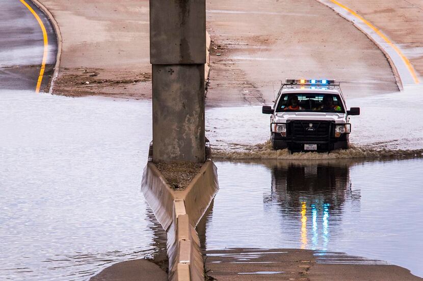 
A Texas Department of Transportation vehicle pushed through remaining floodwaters Saturday...