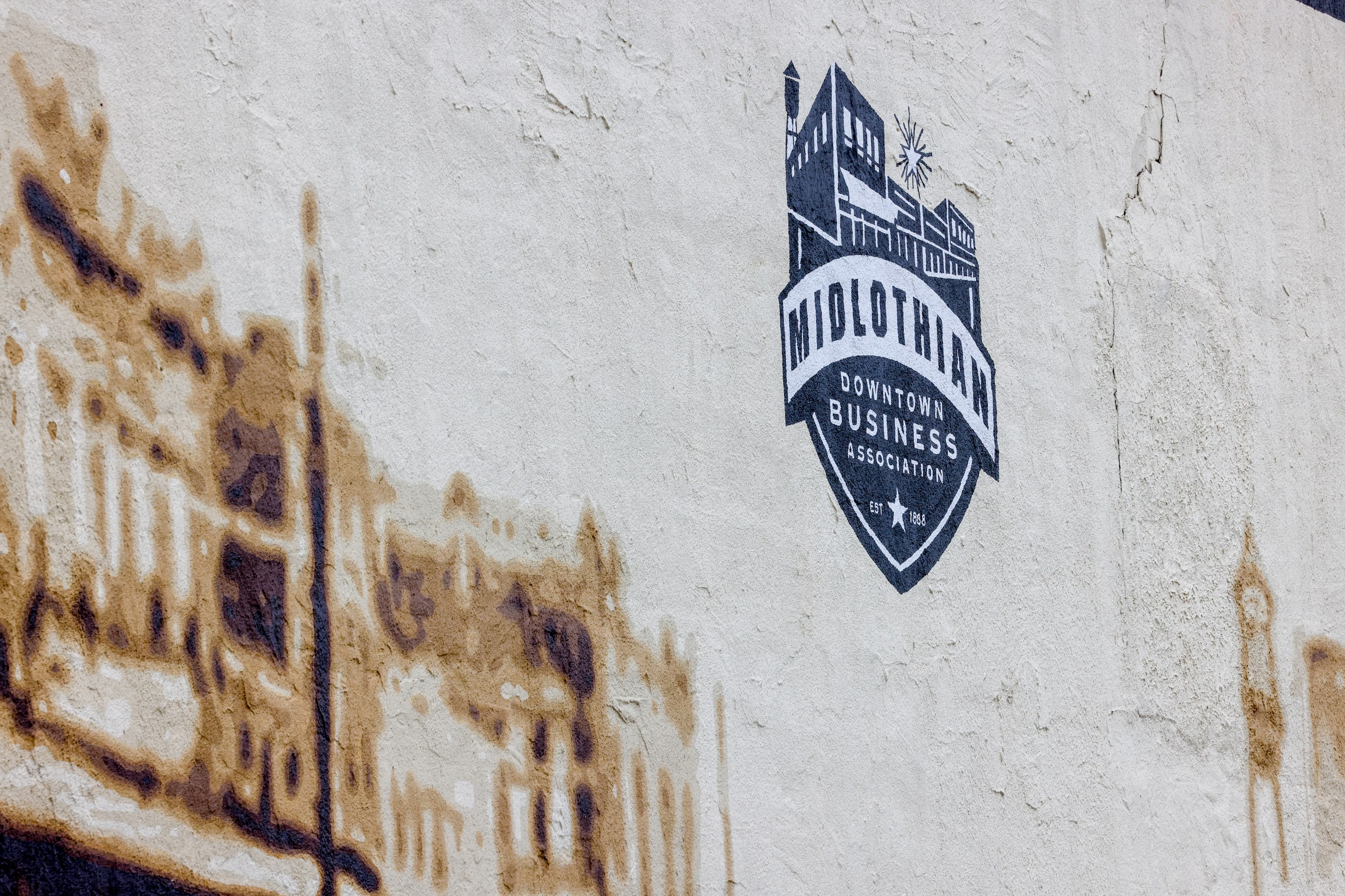 A painted emblem for downtown businesses is displayed on a wall downtown.