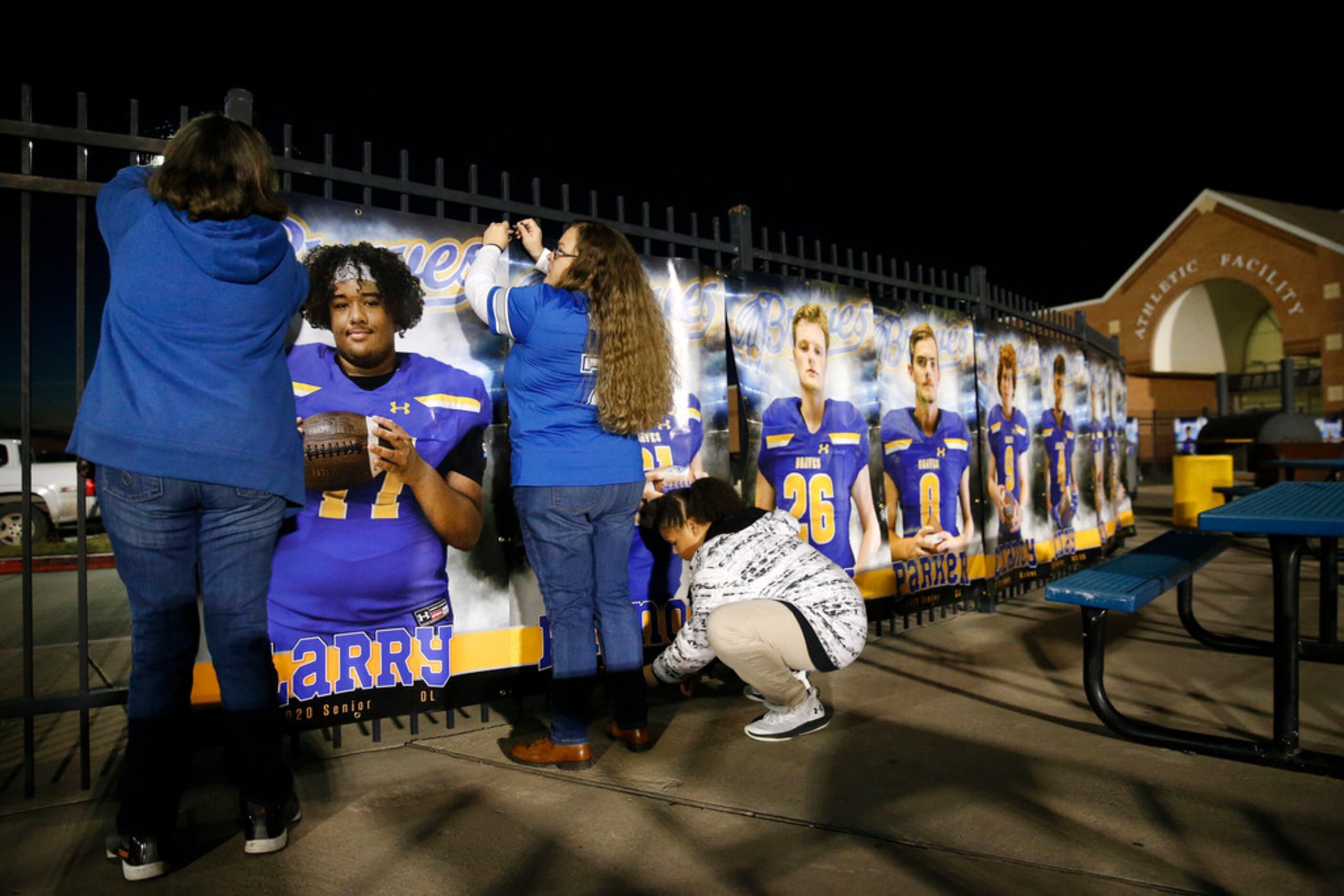 Candace Brown (center) and her mother Teresa Brown (left) hang a photo of her son and senior...